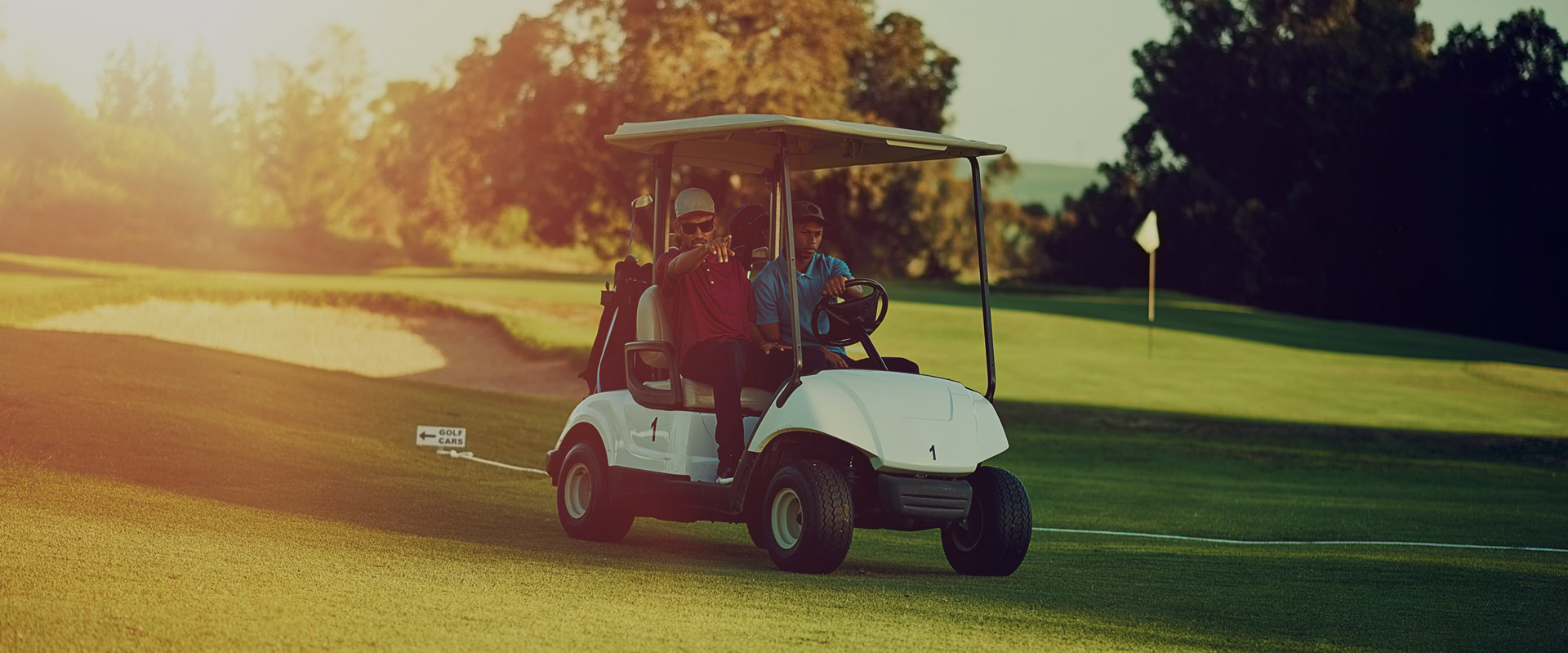 Friends riding in golf cart heading up fairway